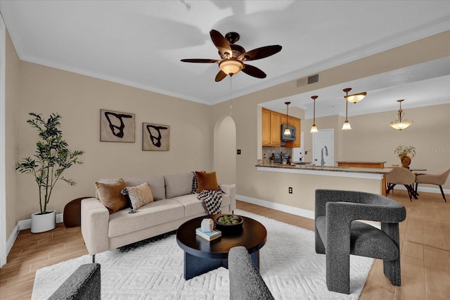 living room featuring visible vents, baseboards, arched walkways, ceiling fan, and light wood-type flooring