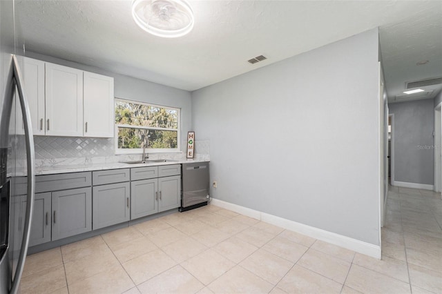 kitchen with visible vents, gray cabinets, a sink, backsplash, and appliances with stainless steel finishes