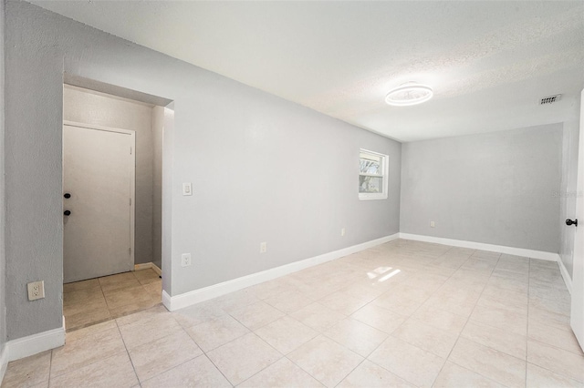 unfurnished room with light tile patterned floors, baseboards, visible vents, and a textured ceiling