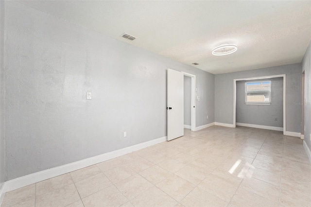 spare room featuring baseboards, visible vents, and a textured ceiling