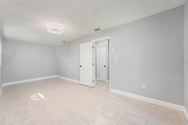 spare room featuring visible vents, baseboards, and a textured ceiling