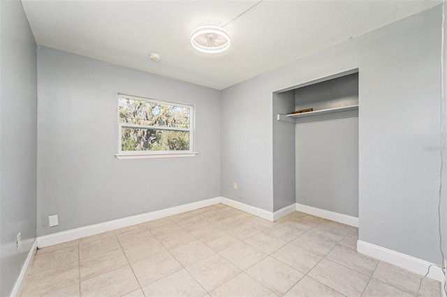 unfurnished bedroom featuring light tile patterned flooring, a closet, and baseboards