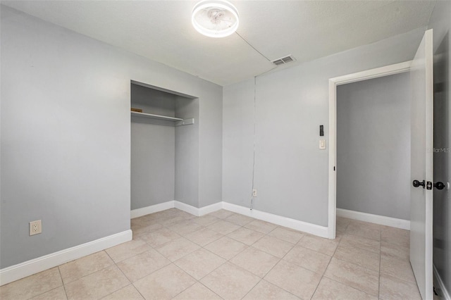 unfurnished bedroom with light tile patterned floors, visible vents, a closet, and baseboards