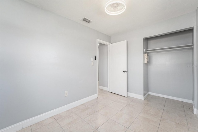 unfurnished bedroom featuring light tile patterned floors, baseboards, visible vents, and a closet