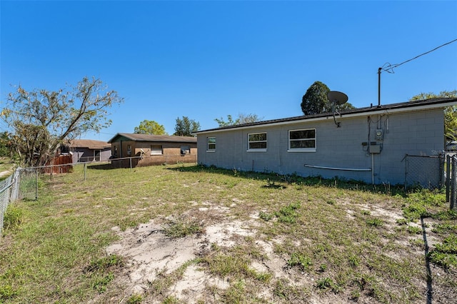 back of house featuring concrete block siding and fence