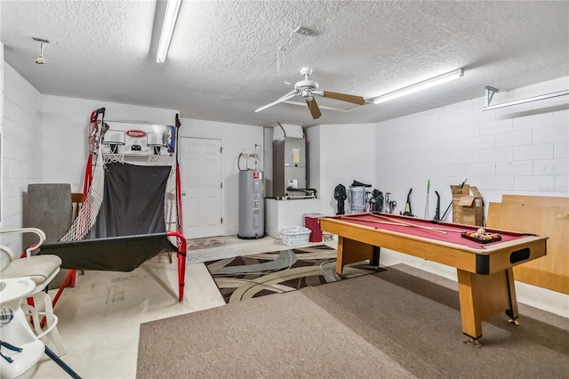 recreation room featuring heating unit, concrete block wall, ceiling fan, a textured ceiling, and electric water heater