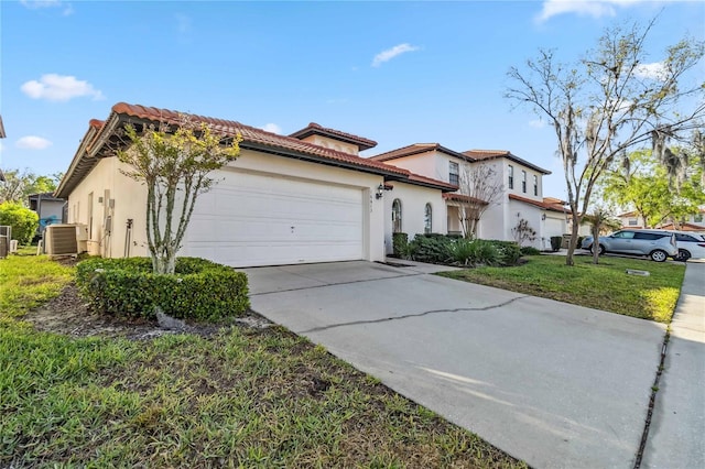 mediterranean / spanish home with central AC unit, driveway, stucco siding, a garage, and a tile roof