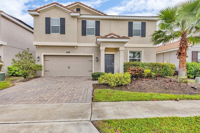 view of front of home with stucco siding, a tile roof, decorative driveway, and a garage