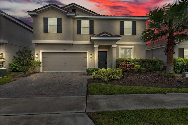 view of front of home featuring stucco siding, decorative driveway, a garage, and a tiled roof