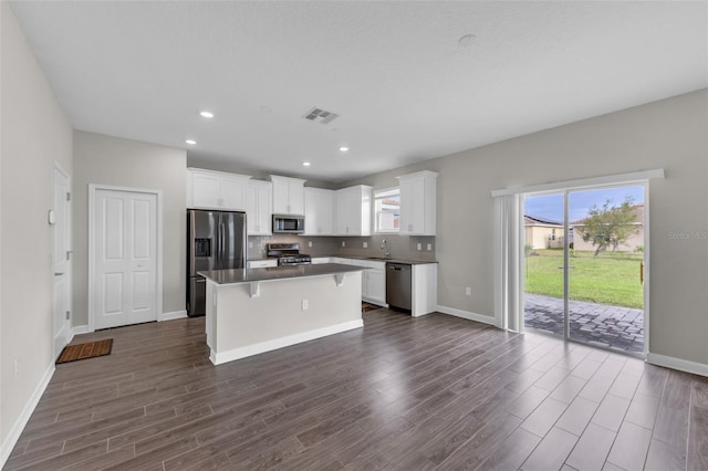 kitchen with dark wood-style floors, visible vents, a kitchen island, stainless steel appliances, and white cabinetry