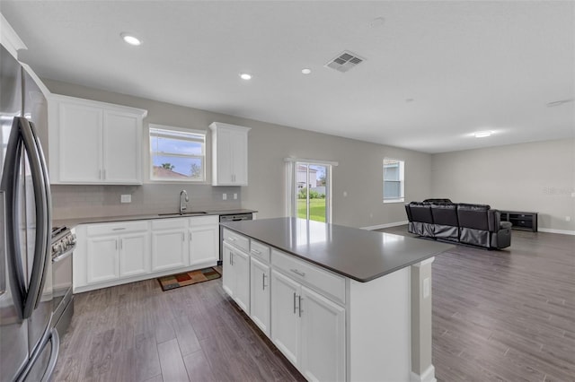 kitchen featuring visible vents, dark wood-type flooring, backsplash, a center island, and stainless steel appliances