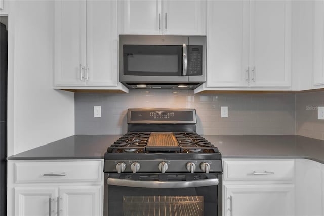 kitchen with dark countertops, backsplash, appliances with stainless steel finishes, and white cabinets