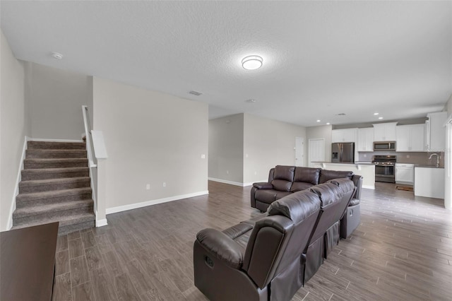 living area with visible vents, baseboards, wood finished floors, and stairs