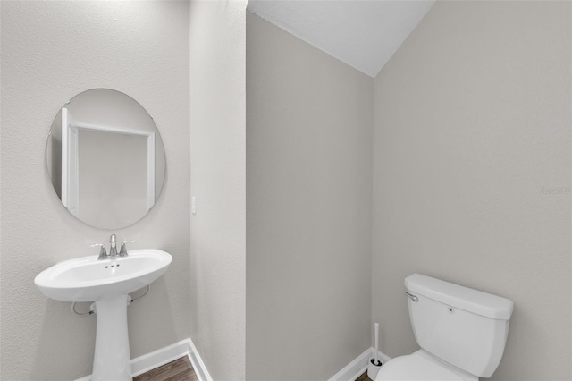 bathroom featuring wood finished floors, toilet, baseboards, and vaulted ceiling