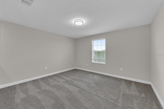 empty room featuring baseboards, visible vents, dark colored carpet, and a textured ceiling