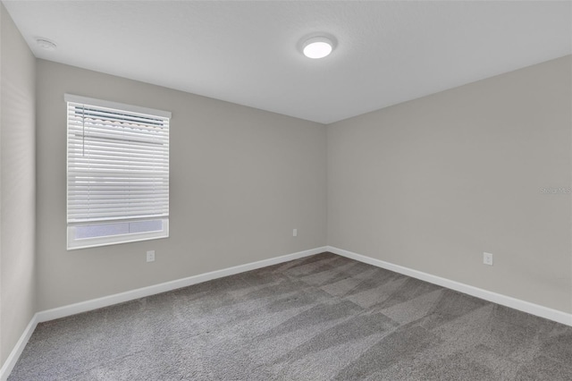 carpeted spare room featuring baseboards