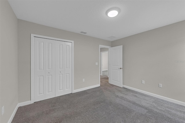 unfurnished bedroom with baseboards, dark colored carpet, and a closet