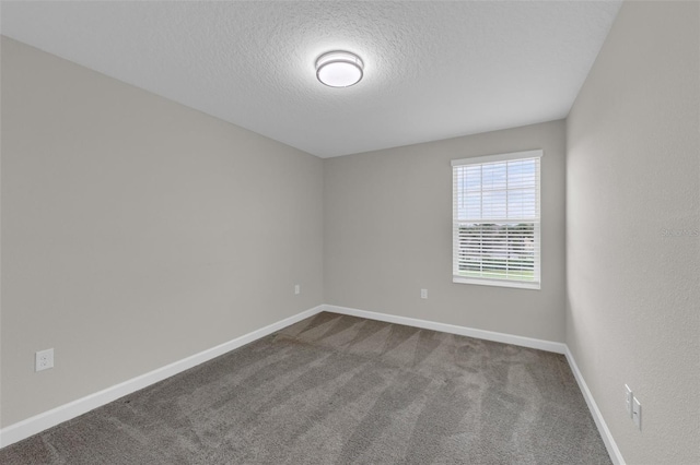 unfurnished room featuring baseboards, dark carpet, and a textured ceiling