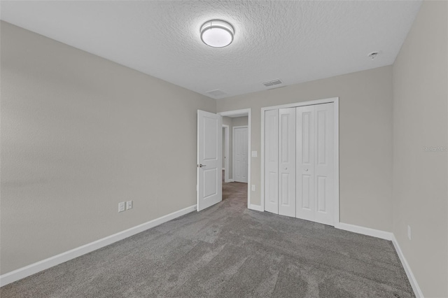 unfurnished bedroom featuring visible vents, a textured ceiling, a closet, carpet floors, and baseboards