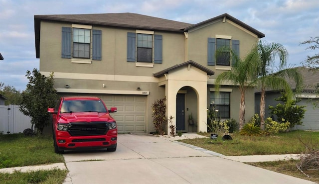 traditional-style house featuring a garage, concrete driveway, fence, and stucco siding