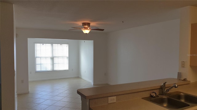 kitchen featuring light tile patterned floors, ceiling fan, a sink, baseboards, and light countertops