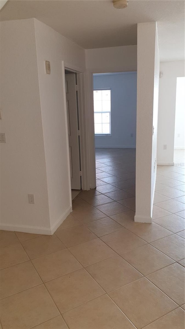 hall with light tile patterned flooring and baseboards