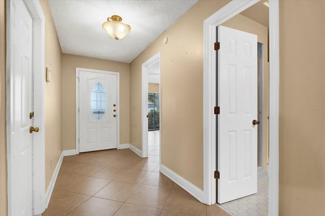 entrance foyer featuring baseboards, a textured ceiling, and light tile patterned flooring