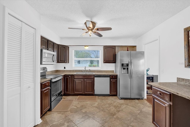 kitchen with dark brown cabinetry, a ceiling fan, appliances with stainless steel finishes, a textured ceiling, and a sink