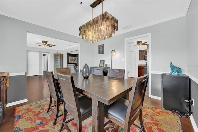 dining area featuring ceiling fan with notable chandelier, visible vents, baseboards, light wood-style floors, and crown molding