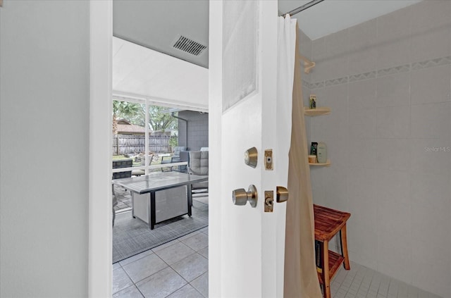 hallway with tile patterned flooring, visible vents, and tile walls