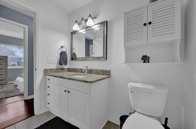 bathroom with toilet, baseboards, connected bathroom, and vanity