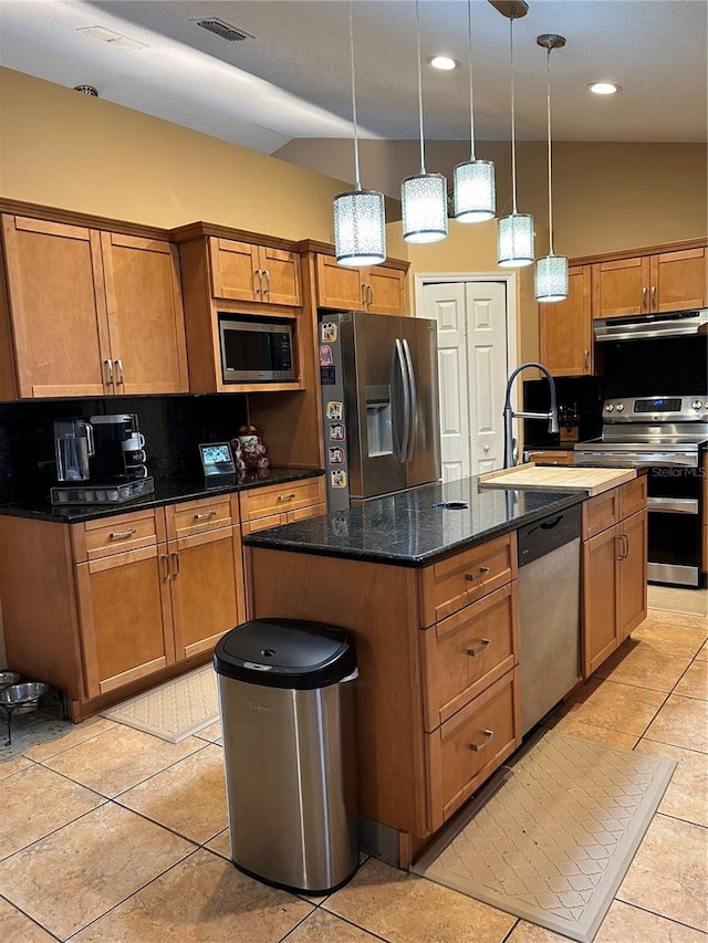 kitchen featuring appliances with stainless steel finishes, brown cabinets, a kitchen island with sink, under cabinet range hood, and a sink