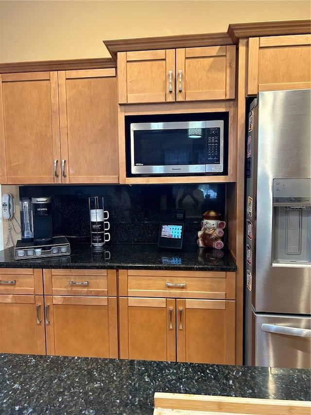 kitchen featuring dark stone countertops, appliances with stainless steel finishes, brown cabinets, and backsplash