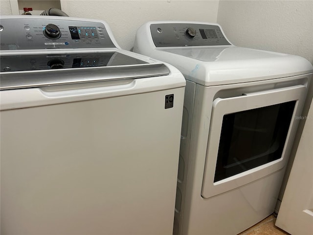 clothes washing area featuring a textured wall and washing machine and dryer