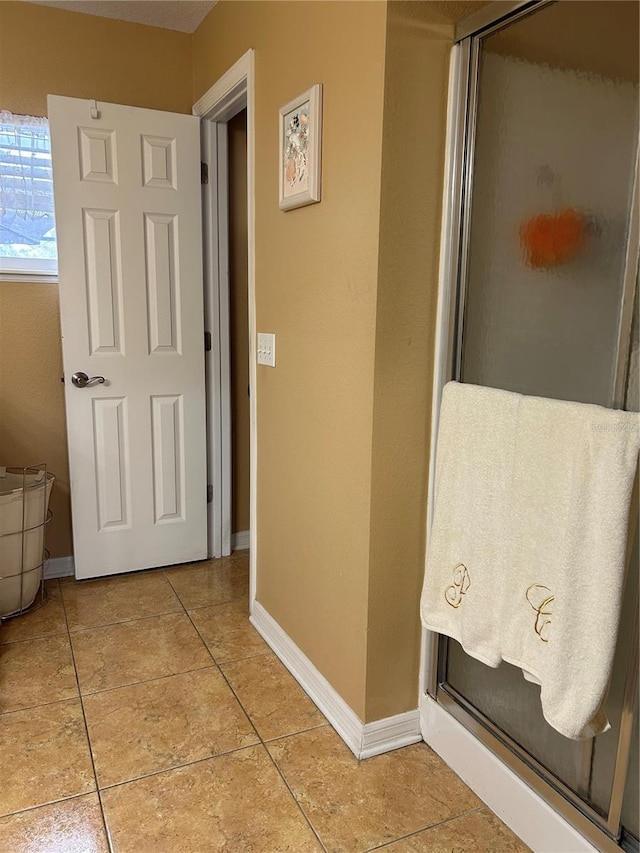 corridor featuring baseboards and light tile patterned floors