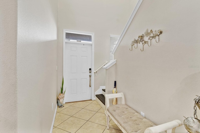 foyer entrance with light tile patterned floors and stairs