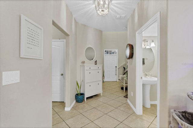 corridor featuring light tile patterned flooring, visible vents, and baseboards