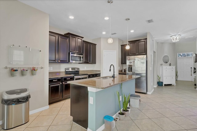 kitchen featuring light tile patterned floors, light stone counters, dark brown cabinetry, stainless steel appliances, and a sink