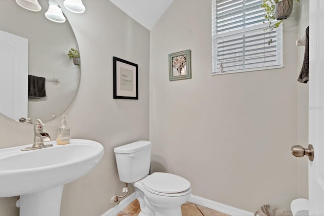 half bath featuring a sink, tile patterned flooring, toilet, and baseboards