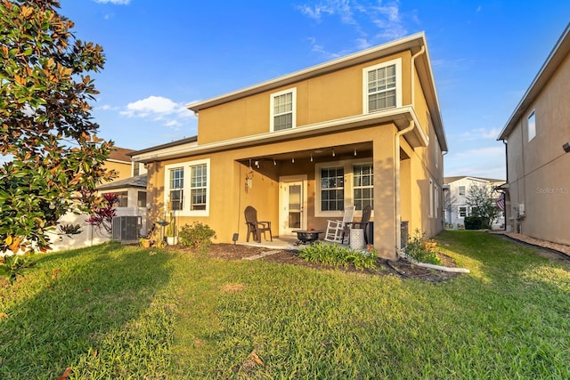 rear view of house with stucco siding, a patio area, a lawn, and central air condition unit