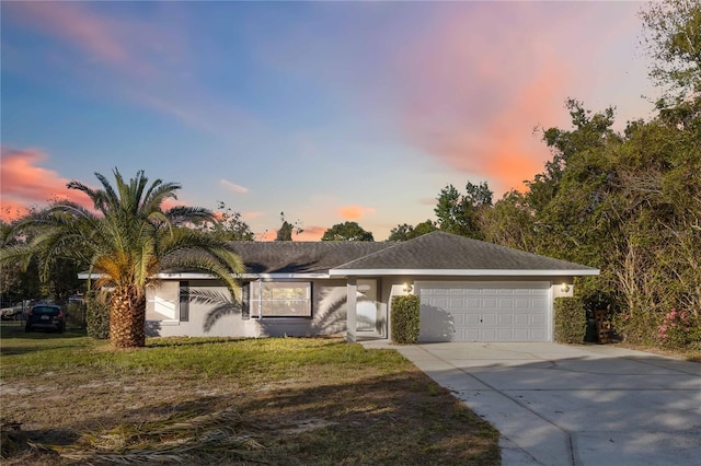 ranch-style house featuring stucco siding, driveway, a front lawn, and a garage