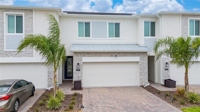 townhome / multi-family property featuring decorative driveway, stone siding, and an attached garage