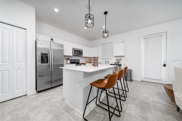 kitchen featuring visible vents, a kitchen island, a kitchen breakfast bar, white cabinets, and stainless steel appliances