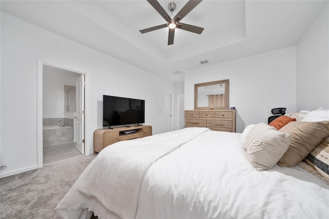 bedroom featuring a raised ceiling, carpet, visible vents, and connected bathroom