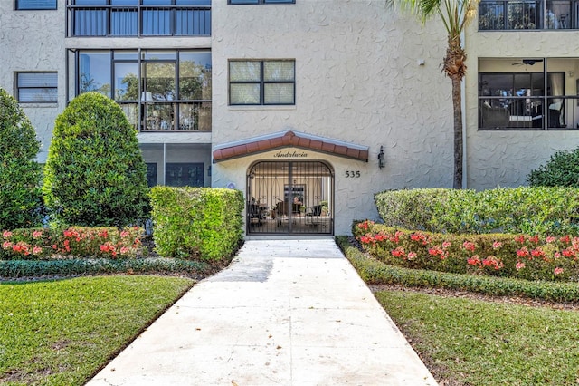 view of exterior entry with stucco siding and a gate