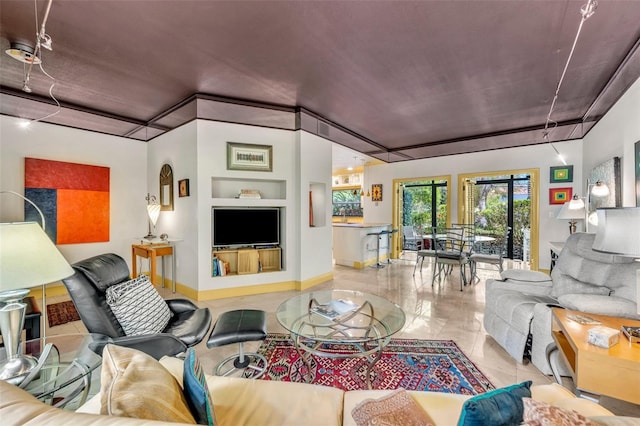 living area featuring tile patterned floors, built in shelves, and baseboards