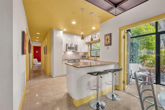 kitchen with dark stone countertops, visible vents, white cabinets, appliances with stainless steel finishes, and tasteful backsplash