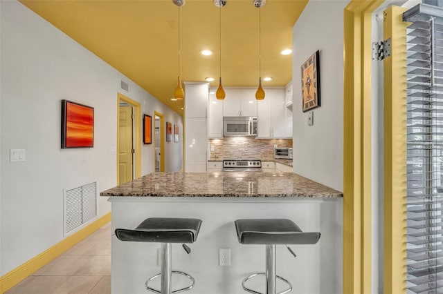 kitchen with visible vents, backsplash, stainless steel appliances, white cabinets, and light tile patterned floors