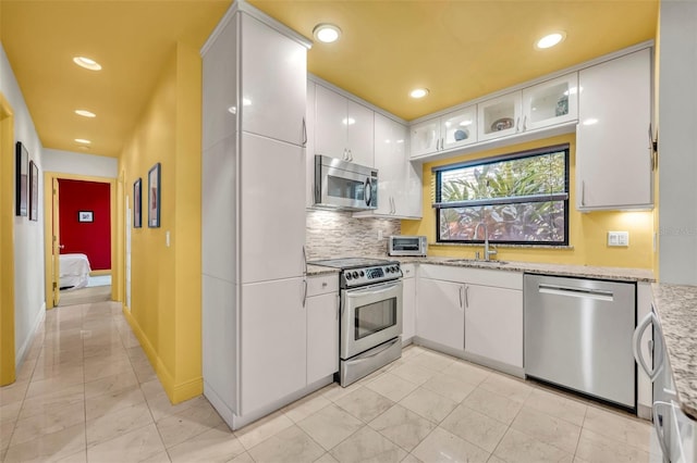 kitchen with light stone counters, stainless steel appliances, tasteful backsplash, and white cabinets