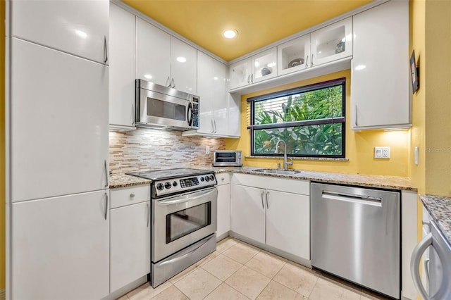 kitchen featuring a sink, decorative backsplash, white cabinets, and stainless steel appliances